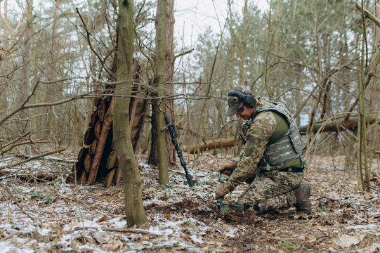 a soldier with a shovel in his hand digs the ground. an infantryman digs a hole