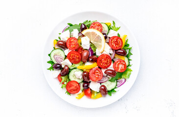 Greek salad with feta cheese, kalamata olives, cherry tomato, yellow paprika, cucumber and onion, healthy mediterranean diet food, low calories eating. White table background, top view