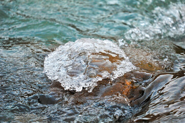 An icy stone washed by the water of a mountain river
