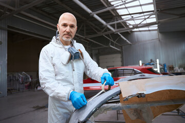 Painter prepares a part of the car body for work