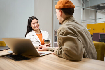 Smiling female office worker communicating with coworker in meeting room