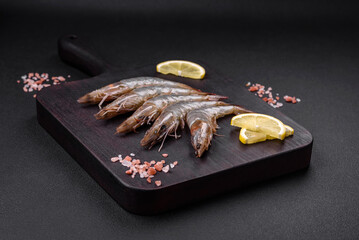Tiger prawn or langoustine raw with spices and salt on a wooden cutting board