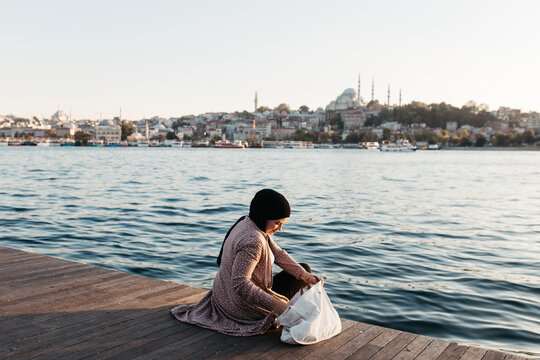 Woman searching her bag while sitting on sea shore