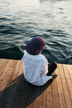 Photo of woman sitting on shore with her legs corssed