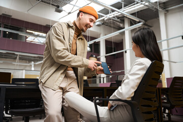 Contented company employee demonstrating something on smartphone to colleague