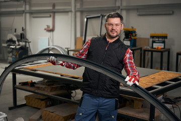 Portrait of male holding metal detail in factory