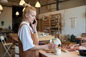 A girl craftsman talks to a client on the phone