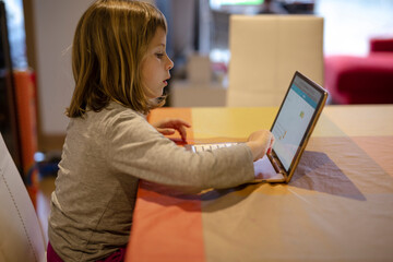 Blonde girl doing her homework on the tablet