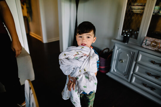 Young boy holds childhood blanket inside home