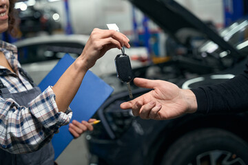 Fototapeta na wymiar Woman auto repairman hands over car keys to client