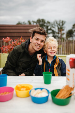 Father and sun enjoing snacks outdoors on a rainy day