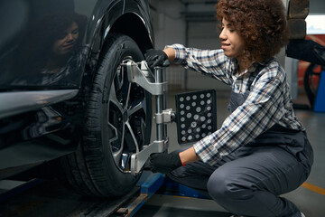 Fototapeta na wymiar Woman auto mechanic repairing a wheel in a car workshop