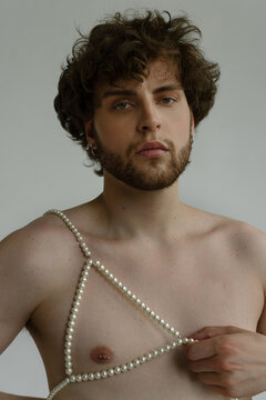 Bearded guy portrait who holds a pearl bra on a naked body