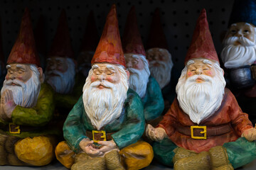 Selective focus view of rows of cute decorative garden gnomes in yoga or meditation poses 