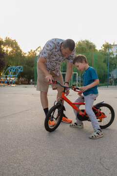 A father is teaching his son how to ride a bicycle 
