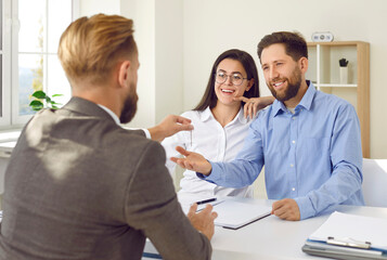 Real estate agent handing over keys to happy family. Professional realtor gives key to happy young...