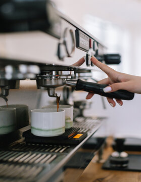 Barista pushing on coffee machine for preparing espresso 