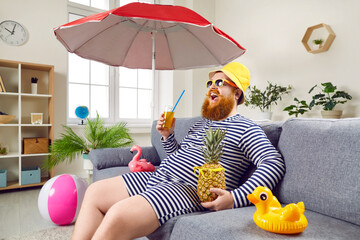 Happy bearded man in classic bathing suit sitting on sofa at home. Excited eccentric man in...