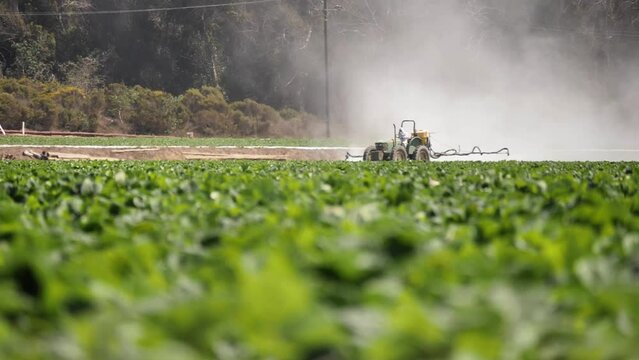 2022 - Distant view of a tractor spraying pesticide on a California farm.