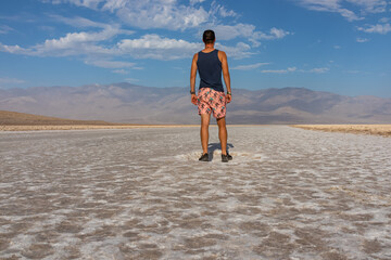 Man looking at scenic view of Badwater Basin salt flats in Death Valley National Park, California, USA. Endorheic basin is lowest, driest, hottest area in North America. Majestic Panamint Mountains