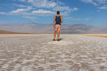 Man looking at scenic view of Badwater Basin salt flats in Death Valley National Park, California, USA. Endorheic basin is lowest, driest, hottest area in North America. Majestic Panamint Mountains