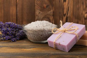 Lavender spa. Essential oils, sea salt, handmade soap, cream and body scrub with lavender flowers on brown texture wood. Natural herbal cosmetics with flowers and lavender aroma.Aromatherapy and relax