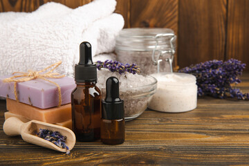 Lavender spa. Essential oils, sea salt, handmade soap, cream and body scrub with lavender flowers on brown texture wood. Natural herbal cosmetics with flowers and lavender aroma.Aromatherapy and relax