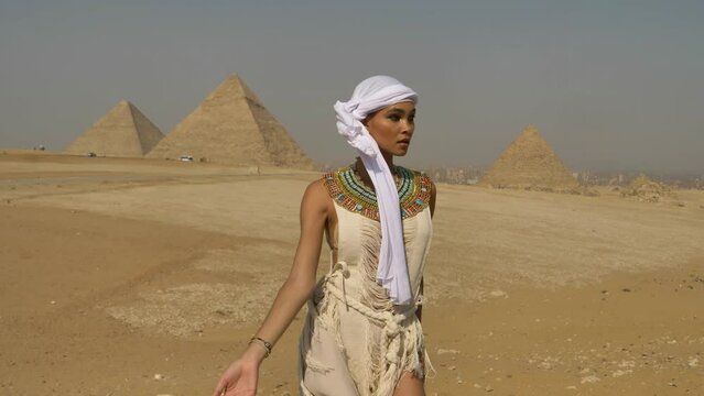 2022 - An interpretive dancer in Egyptian jewelry performs in the breeze before pyramids in Egypt.