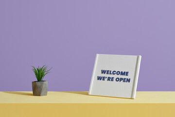 A 'Welcome We're Open' sign on table of a shop