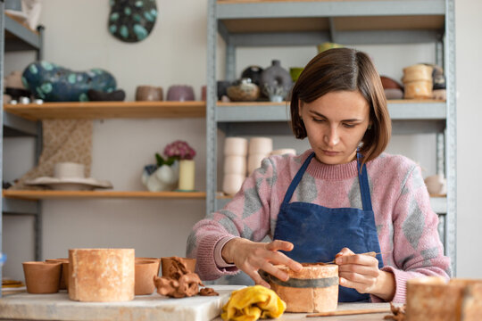 the girl takes the excess clay from the mold