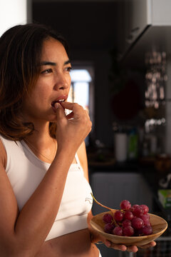 Woman biting grape with natural light