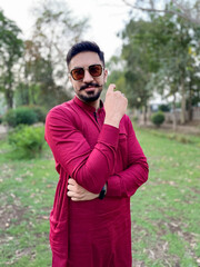 young man strong happy cheery sports man posing outdoors in nature green park looking at camera posing