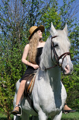 teenage girl with long hair horseback riding in sunny day