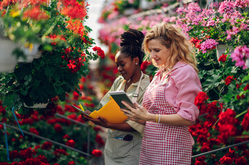 Multiracial woman gardeners working in a greenhouse and using tablet