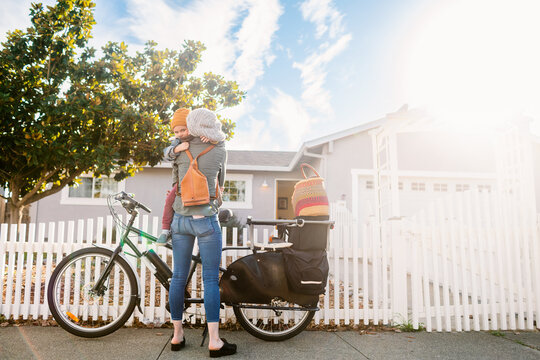 Mother and son with bike in front home