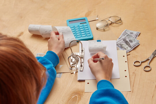 Woman writing expenses with payment receipts.