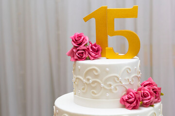 Bolo de aniversário de quinze anos e mesa decorada com flores e plantas.