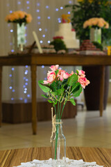 Decoração com flores e mesa do bolo de aniversário ao fundo. 