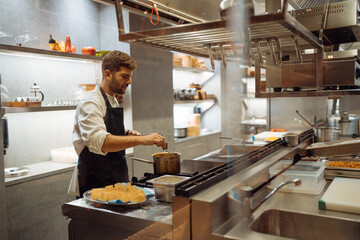 Man mixing food in pan in restaurant kitchen