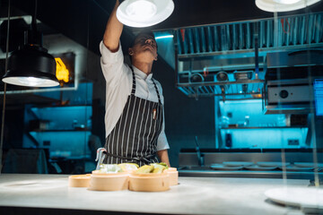 Male chef adjusting lamp over table