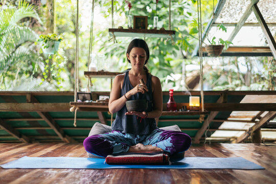 Woman meditating and doing yoga with singing bowls