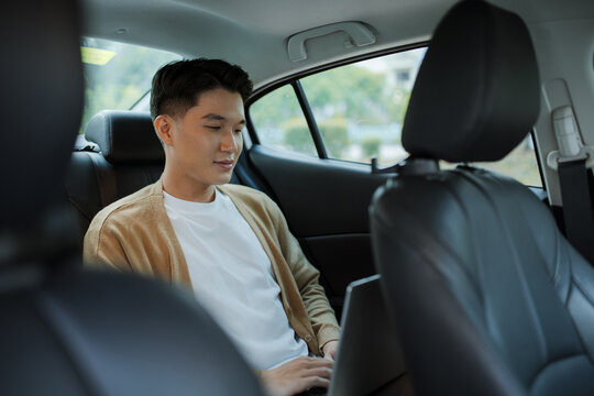 Handsome Young businessman using laptop and sitting in back seat