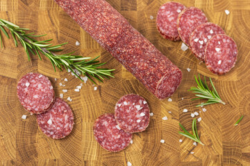Sausage on a wooden board. Sausage with raspberry and salt. Sausage on top. Macro Sausage