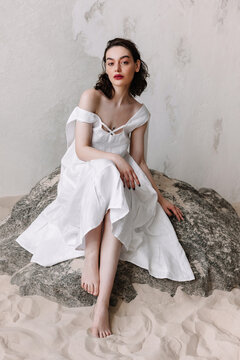Sensual woman in dress sitting on stone