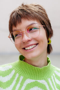 Cheerful young woman in eyeglasses. Beautiful Smile with tooth gems