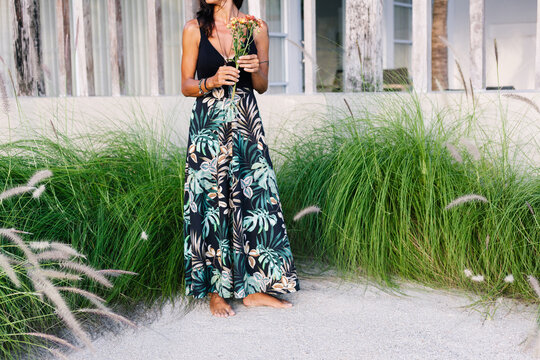 Crop woman in summer floral dress posing at beach tropic resort