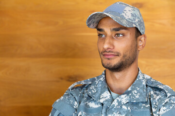Happy biracial male soldier wearing military uniform, looking away and smiling, with copy space