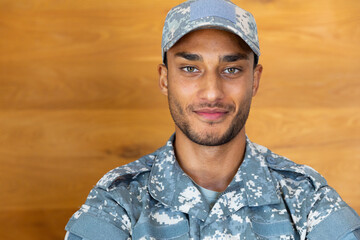 Portrait of happy biracial male soldier wearing military uniform and cap, looking at camera