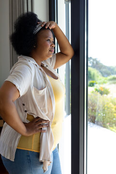 Thoughtful Plus Size African American Woman Leaning And Looking Out Of Window