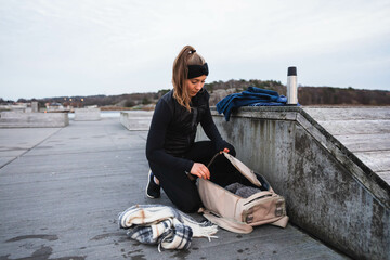 Young woman packing her backpack outside